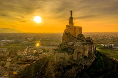 Monteagudo kalesinin hava günbatımı görüntüsü, Murcia İspanya yakınlarındaki dağın şeklini takip eden iki kaplamayla birlikte, çarpık topraktan inşa edilmiş. 