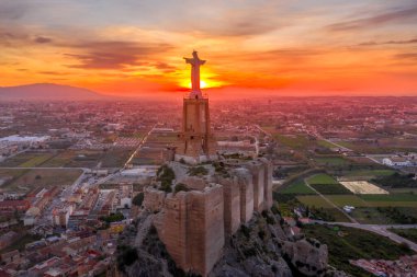 Monteagudo kalesinin hava günbatımı görüntüsü, Murcia İspanya yakınlarındaki dağın şeklini takip eden iki kaplamayla birlikte, çarpık topraktan inşa edilmiş. 