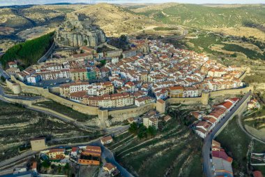 Morella 'nın gökyüzü mavi gökyüzüyle güneşli bir kış öğleden sonrasında surlar ve kulelerle çevrili ortaçağ kasabasının havadan görünüşü.