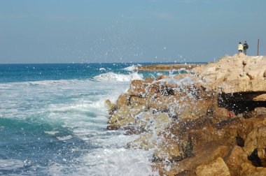 Sörf, deniz kıyısı, dalgalar köpüklü kayalar mavi su püskürtür