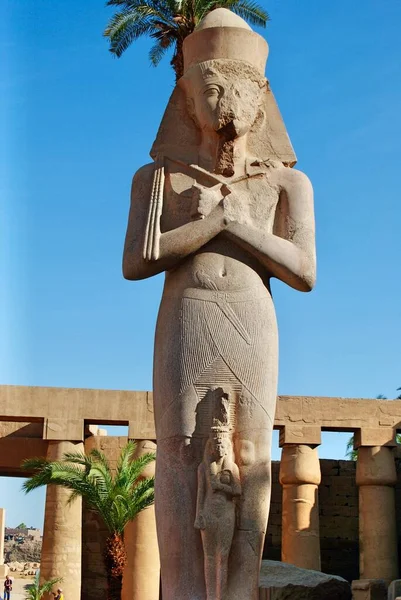Turista masculino não identificado caminhando em direção à estátua colossal do faraó Ramsés II e da princesa-rainha Meritamen no Templo de Luxor, datado de 1400 aC. Luxor Egipto. Património Mundial da UNESCO. — Fotografia de Stock