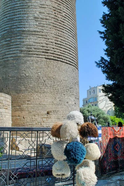 Une exposition de chapeaux et chiffons traditionnels azerbaïdjanais et caucasiens en laine de mouton souvenir Papakha devant la Tour de la Vierge. La ville fortifiée de Bakou, Azerbaïdjan. Site du patrimoine mondial de l'UNESCO. — Photo