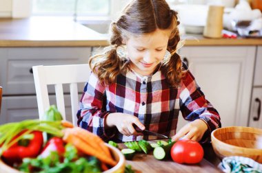 kız çocuk anne yemek ve salata için taze sebze bıçak ile kesmek için yardımcı olur. Çocuklar evi öğrenme çiftlikte yaz tatillerini üzerinde çalışmak.
