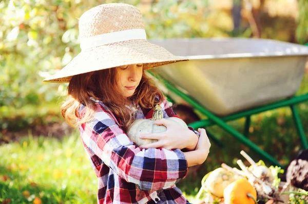 農民の帽子と シャツの再生と日当たりの良いガーデンで秋野菜の収穫を選ぶ幸せな面白い子女の子 有機にんじん カボチャを成長 — ストック写真