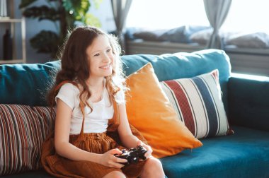video oyunları evde, gamepad ile modern iç rahat koltukta oturan oynayan mutlu çocuk