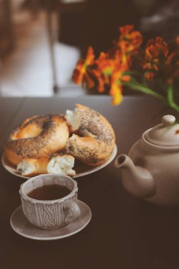 kır evi tablo üzerinde sıcak sonbahar kahvaltı. Sıcak çay, simit ve koyu kahverengi masaya çiçek