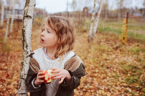 快乐滑稽的女孩吃新鲜的苹果在秋天森林 坐在白桦木栈 秋季收获与有机食品概念 — 图库照片