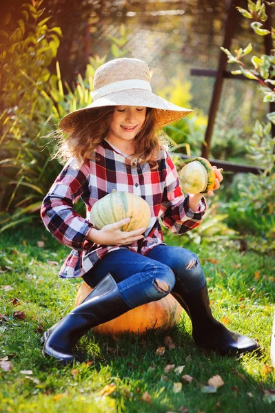 農民の帽子と シャツの再生と日当たりの良いガーデンで秋野菜の収穫を選ぶ幸せな面白い子女の子 有機にんじん カボチャを成長 — ストック写真