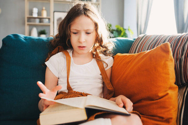 concentrated child girl reading interesting book at home