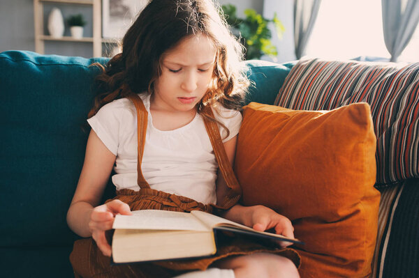 concentrated child girl reading interesting book at home