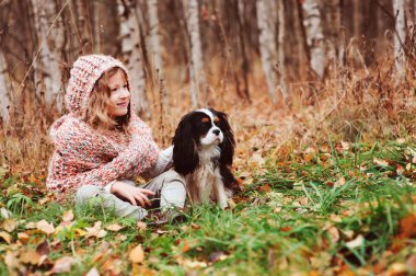 cavalier king charles spaniel köpeği ile sonbaharda, yürüyüş güneşli bahçe veya ormanında açık oynayan mutlu çocuk kız