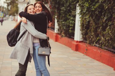 iki genç mutlu kız rahat moda kıyafetler içinde şehrin sokaklarında yürürken, sıcak palto giyen ve having fun