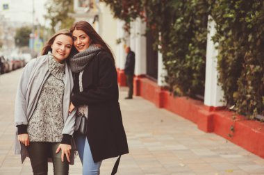 iki genç mutlu kız rahat moda kıyafetler içinde şehrin sokaklarında yürürken, sıcak palto giyen ve having fun