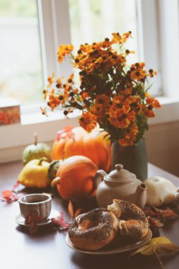 kır evi tablo üzerinde sıcak sonbahar kahvaltı. Sıcak çay, pumpkins, simit ve çiçekler.