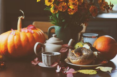 kır evi tablo üzerinde sıcak sonbahar kahvaltı. Sıcak çay, pumpkins, simit ve çiçekler.