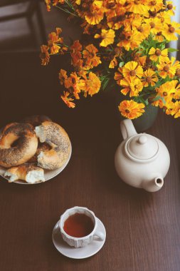 kır evi tablo üzerinde sıcak sonbahar kahvaltı. Sıcak çay, simit ve koyu kahverengi masaya çiçek