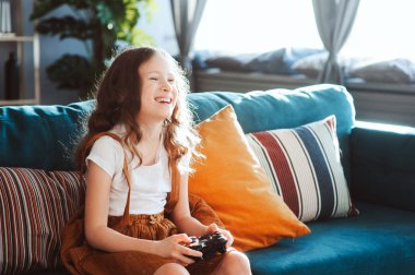 video oyunları evde, gamepad ile modern iç rahat koltukta oturan oynayan mutlu çocuk
