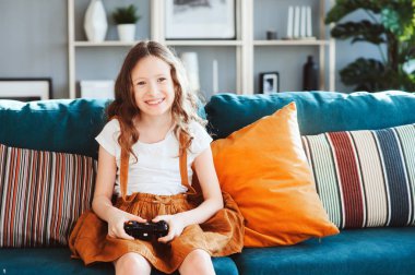 video oyunları evde, gamepad ile modern iç rahat koltukta oturan oynayan mutlu çocuk