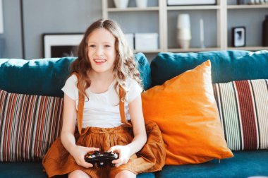 video oyunları evde, gamepad ile modern iç rahat koltukta oturan oynayan mutlu çocuk