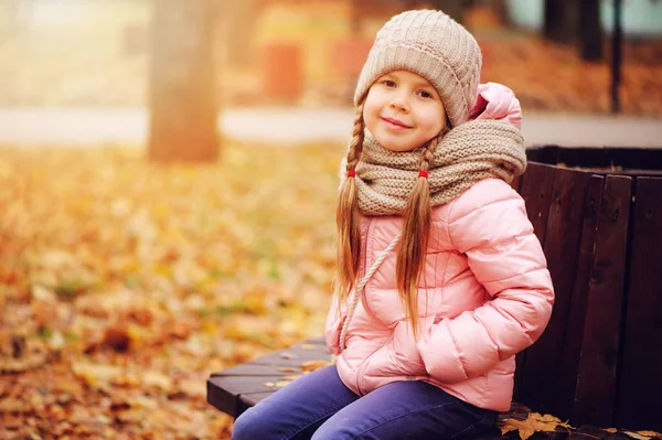 秋天的微笑的女孩的肖像坐在公园的长凳上温暖的针织帽子和围巾 享受户外散步在阳光明媚的日子里 — 图库照片