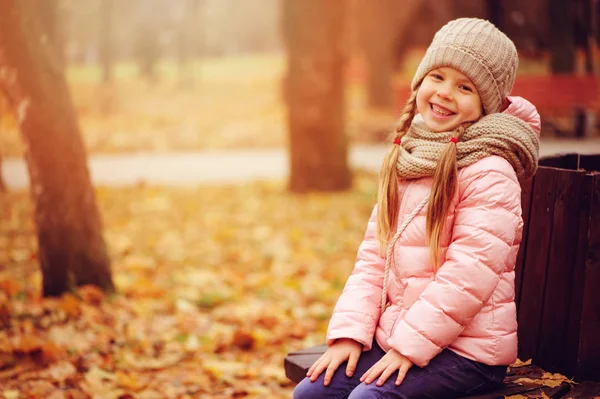 晴れた日の屋外散歩を楽しんで暖かいニット帽子とスカーフ 公園のベンチに座っている子供の女の子の笑顔秋の肖像画 — ストック写真