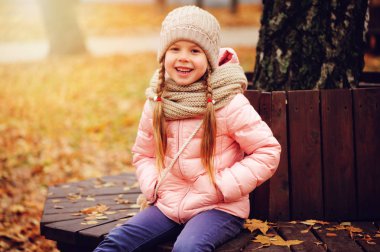 gülümseyen güneşli günde açık yürüyüş zevk sıcak örme şapka ve atkı, parkta bankta oturmuş kız çocuk sonbahar portresi