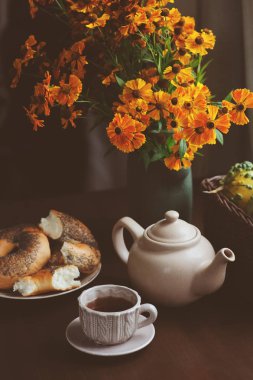 kır evi tablo üzerinde sıcak sonbahar kahvaltı. Sıcak çay, simit ve koyu kahverengi masaya çiçek