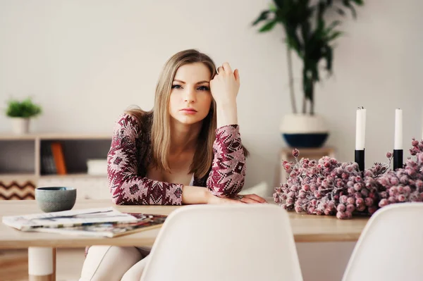 young beautiful woman relaxing at home in the morning, having breakfast in modern loft kitchen with scandinavian interior