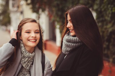 iki genç mutlu kız rahat moda kıyafetler içinde şehrin sokaklarında yürürken, sıcak palto giyen ve having fun