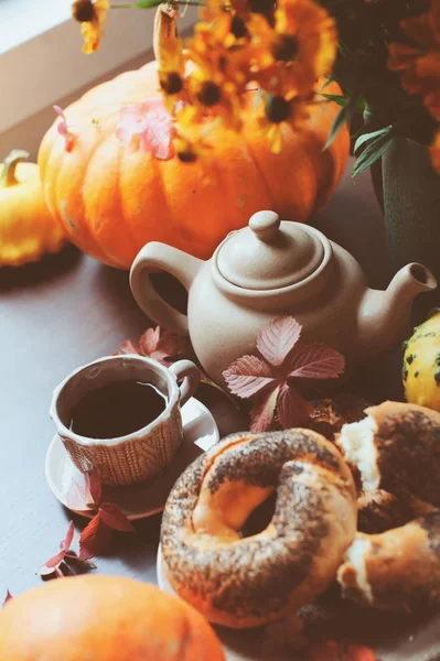 cozy autumn breakfast on table in country house. Hot tea, pumpkins, bagels and flowers.