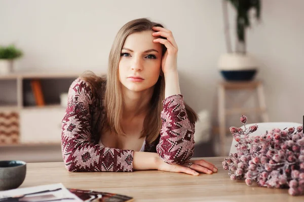 young beautiful woman relaxing at home in the morning, having breakfast in modern loft kitchen with scandinavian interior