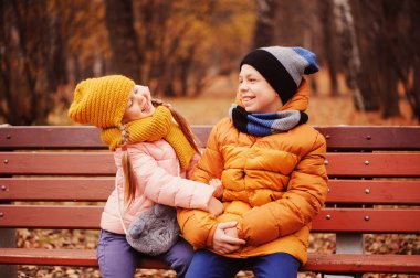mutlu çocuk, kız ve erkek kardeşim park ve hugs bankta oturmuş sonbahar portresi