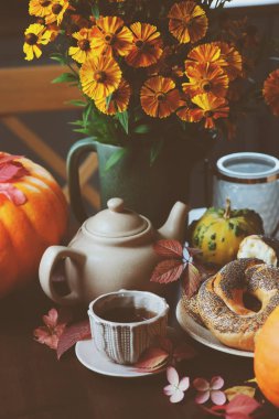 kır evi tablo üzerinde sıcak sonbahar kahvaltı. Sıcak çay, pumpkins, simit ve çiçekler.