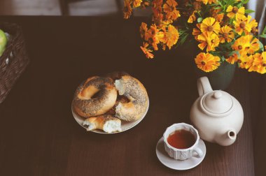 kır evi tablo üzerinde sıcak sonbahar kahvaltı. Sıcak çay, simit ve koyu kahverengi masaya çiçek