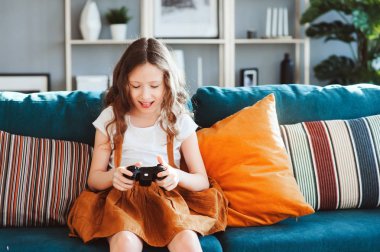 video oyunları evde, gamepad ile modern iç rahat koltukta oturan oynayan mutlu çocuk