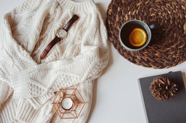 sonbahar ya da kış rahat natürmort küme. Sıcak örme kazak, fincan limonlu çay ve beyaz arka plan üzerinde çam kozalağı ile kitap. Hygge kavramı.