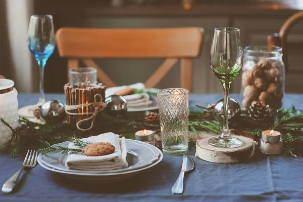 Şenlikli Noel ve Yeni Yıl sofrası İskandinav tarzında hazırlandı. Kırsal ve beyaz tonlarda el yapımı detaylarla. Çam kozalakları, dallar ve mumlarla süslenmiş yemek salonu.