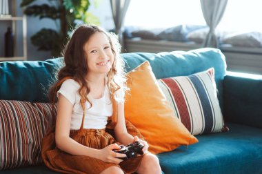 video oyunları evde, gamepad ile modern iç rahat koltukta oturan oynayan mutlu çocuk