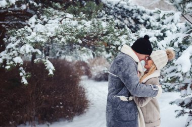 romantik çift öpüşme karlı ormanda kış portresi. Sevgililer günü veya tatil kavramı.