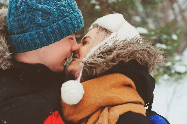 eğlenceli ve öpücük sahip karlı kış ormanda yürüyüş mutlu genç sevgi dolu bir çift. Etkin kış tatil açık.