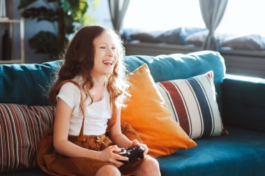 video oyunları evde, gamepad ile modern iç rahat koltukta oturan oynayan mutlu çocuk