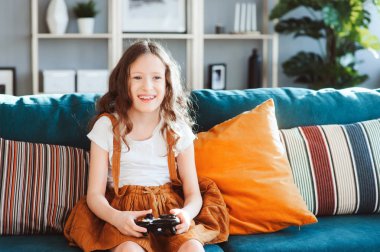 video oyunları evde, gamepad ile modern iç rahat koltukta oturan oynayan mutlu çocuk