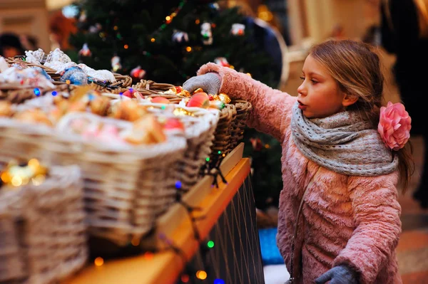 child girl choosing christmas gifts on holiday market
