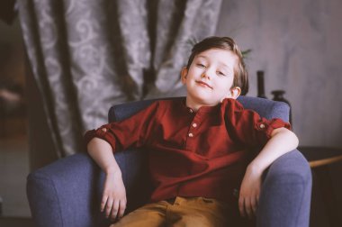 kapalı sandalyede oturan mutlu yakışıklı şık çocuk çocuk portresi 