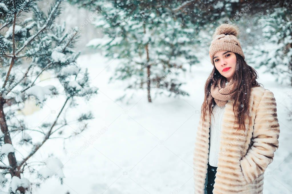 happy young woman walking under the pine trees in snowy winter forest. Seasonal activities and winter vacations concept