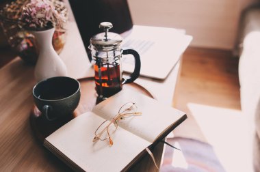 evde laptop, sıcak çay ve defter ile rahatlatıcı. Hafta sonu sabah, modern yaşam tarzı rahat.