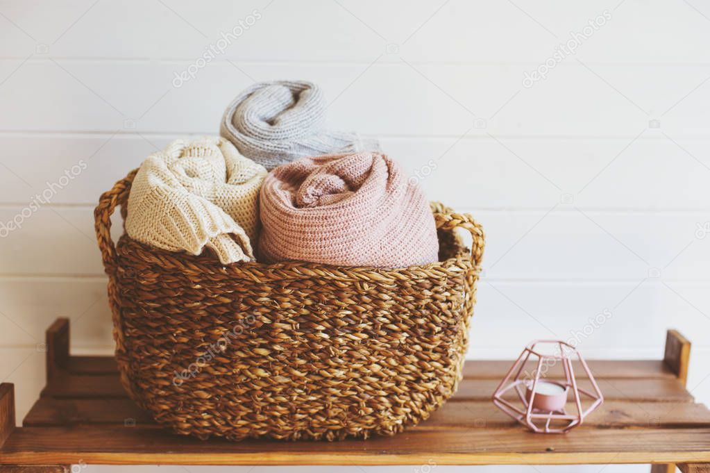 cozy interior details, scandinavian mininalistic lifestyle. Organizing clothes in wicker backets, seasonal wardrobe and house cleaning, ideas for winter season.