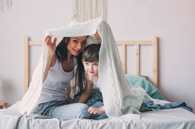 mutlu anne ve oğlu oynayan ve sıcak hafta sonu sabah yatakta battaniyenin altında saklanıyor. Gerçek aile ile rahat yaşam tarzı