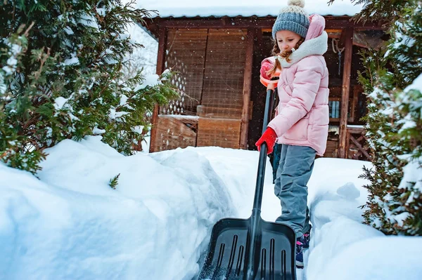 小女孩帮助清洁的路径从雪与 Showel 在雪冬花园里玩耍的孩子 — 图库照片