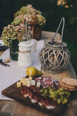 Yaz açık masa meyve ve şarap gözlük ile kesme tahtası üzerinde peynir ve ham plaka ile. Romantik bir akşam yemeği açık